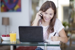 Happy woman working at home and talking to a customer