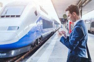 man using mobile application on his smartphone at train station, business travel